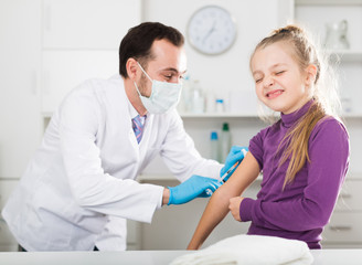 Male doctor injecting little patient