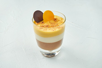 Puff dessert in a glass with milk, chocolate and passion fruit on a white texture background