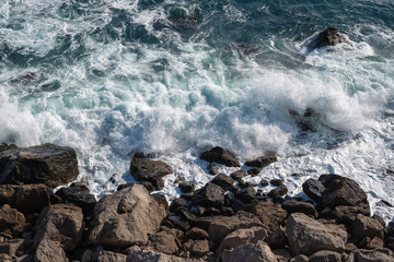 Fototapeta na wymiar Sea waves breaking on the rocky shore, view from top