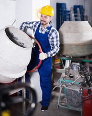 Young smiling worker using concrete mixer