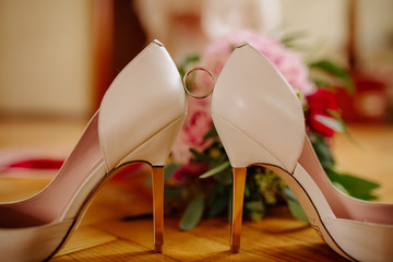 female feet in white wedding sandals with a bouquet of camomiles
