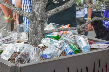 Garbage from cans and plastic and paper in a pot with a tree