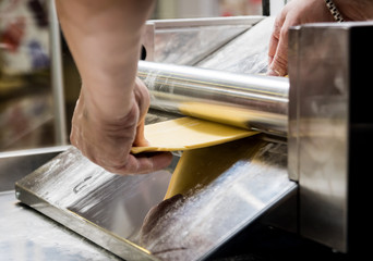 Chef rolling dough with a pasta machine. Pasta maker machine. 