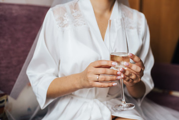 A girl in a white dressing-gown gets on the hip glass of champagne