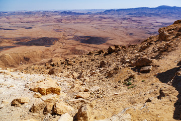 Fototapeta na wymiar Rocky slope with cobblestones. On the horizon endless and lifeless desert. Deserted view during the day.
