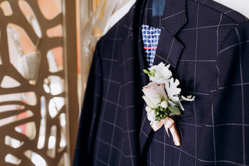 A blue jacket with a buttonhole on the chest hangs on a screen