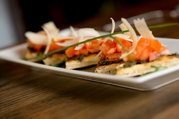 Bruschetta with olive and garlic pesto, with cherry tomato and parmesan leaves