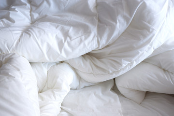 Fototapeta na wymiar Soft white blanket. The sun's rays fall on the bed linen. Cosiness