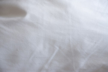 Soft white blanket. The sun's rays fall on the bed linen. Cosiness