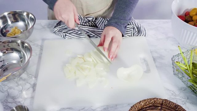 Step by step. Cutting vegetables on a white cutting board to make a one-pot pasta recipe.