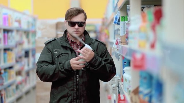 A young man in a black jacket and sunglasses steals in a store