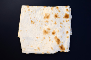 Thin pita leaf folded top view. Pita bread on a black background. Thin homemade pita bread without yeast