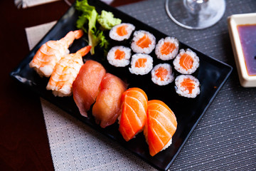 Various sushi served on black plate. Japanese food