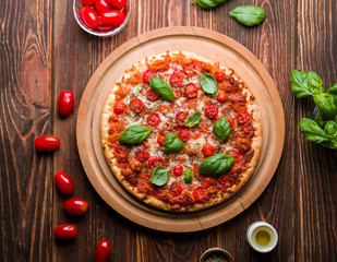 Delicious pizza with tomatoes and basil on wood.