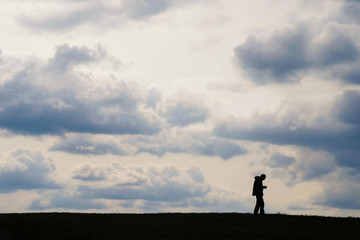 Silhouette of a man with a phone on a hill on a background of clouds in Ukraine. Information transfer concept.