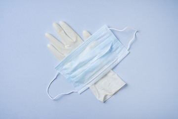 the face mask and medical glove are on a blue background. Covid-19 pandemic, essential goods, scarcity