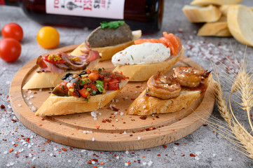 Assorted bruschetta with various toppings on a gray concrete table