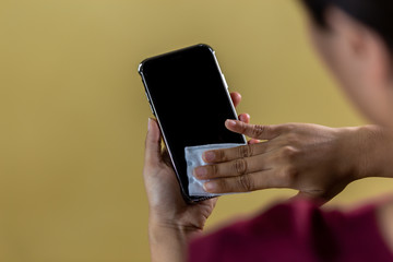 Woman's hand wiping the phone with gel to kill covid 19