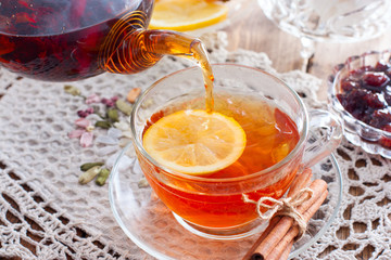 Black tea with cinnamon and lemon in a glass cup on a wooden table, horizontal