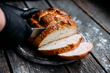 Wheat flour bread on the table. The cook cuts the bread.