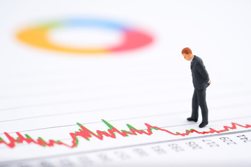 Miniature people:Businessman look at the stock trend (increase or decrease) with copy space. Financial crisis. Data analysis. Stock market volatility risk. Information for investment. Finance concept.