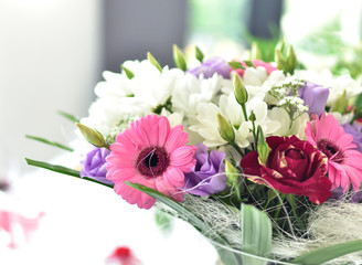 Wedding bouquet with pink and purple flowers on white tablecloth.