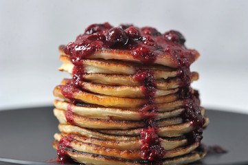 Pancakes with berry jam on a black plate. Close-up. Macro shot.