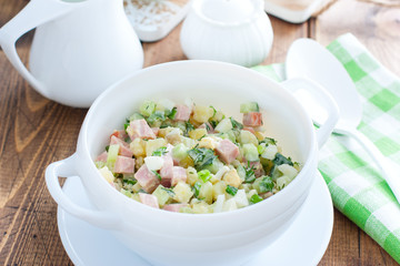 Traditional summer okroshka soup with sausage in a white bowl, selective focus