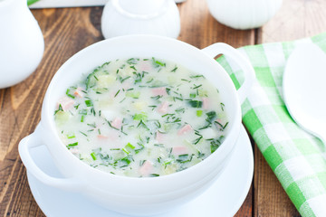Traditional summer okroshka soup with sausage in a white bowl, selective focus
