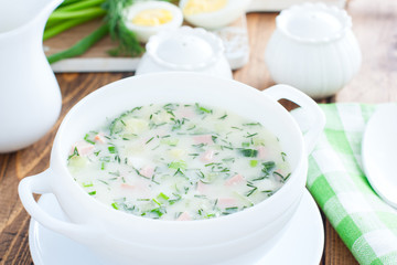 Traditional summer okroshka soup with sausage in a white bowl, selective focus