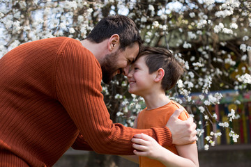 Father and son hugging outdoors, shallow depth of field