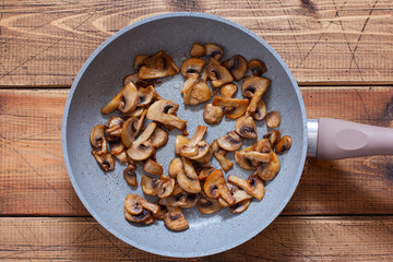 Step-by-step preparation of risotto with mushrooms and chicken breast, step 2 - frying chopped champignons, top view, selective focus