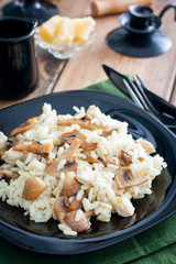 Risotto with chicken and champignons on a black plate, selective focus