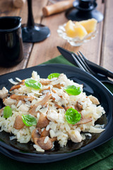 Risotto with chicken and champignons on a black plate, selective focus