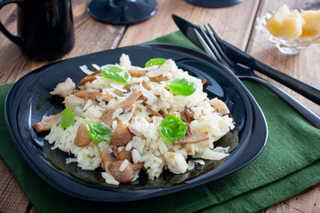 Risotto with chicken and champignons on a black plate, selective focus