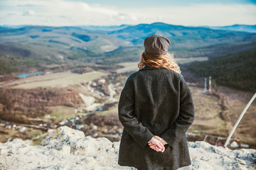 the girl stands with her back to the frame and looks at the landscape