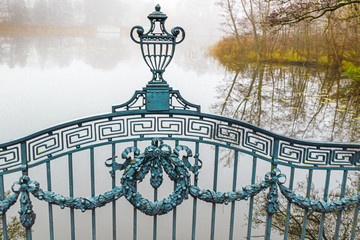 Neblige Landschaft mit verspieltem Ziergitter einer Brücke 
