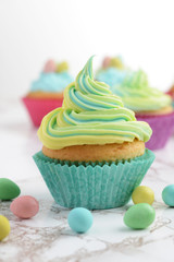 closeup of colorful yellow and blue easter swirl cupcake with mini eggs
