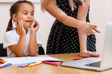 The little girl is studying. School kids work at lesson. Teacher controlling learning process.