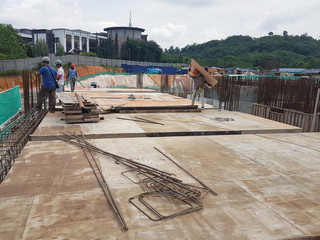 Building floor slab under construction. Construction workers fabricating the timber formwork and installing the steel reinforcement bar.