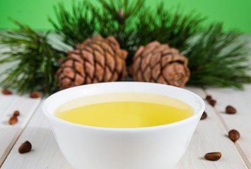 natural production concept, pine cone with nuts and butter on a white wooden table