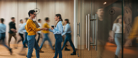 Business people handshaking on background of crowd office employees at coworking center. People at motion blur. Concept of working at action. Group of coworkers at open space. Wide image