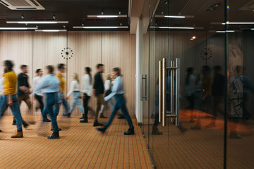 Group of office employees at coworking hall. Business people walking at modern open space. Motion...