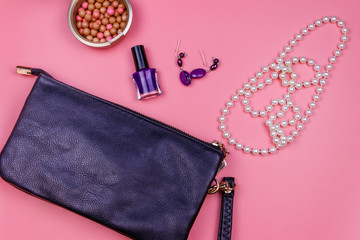 Clutch bag, pearl necklace, earrings, nail polish and rouge balls on pink background. Beauty and fashion concept. Flat lay, top view