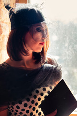 Portrait near window of woman in vintage style with veil