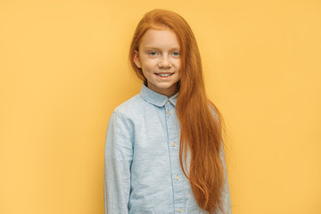 portrait of cheerful positive red haired girl isolated over yellow background. open-minded girl 6 years old look at camera, smile. natural beauty concept