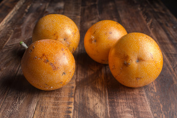 Sweet granadilla or grenadia passion fruit on wooden board. Whole exotic fruits