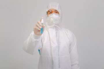 Male doctor wears protective suit, medical gloves and medical masks holding alcohol spray on gray...