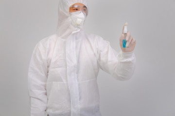 Male doctor wears protective suit, medical gloves and medical masks holding alcohol spray on gray background, corona virus concept, covid19 concept, medical concept