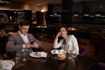young caucasian woman take offense at her boyfriend in restaurant, came to have dinner, as a result they don't talk